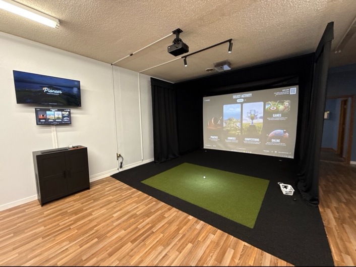 Actual Smooth Swing Golf Simulator room with full black simulator enclosure, projection screen and green hitting mat